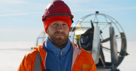 Close up portrait of handsome bearded lifeguard putting on hardhat posing at camera