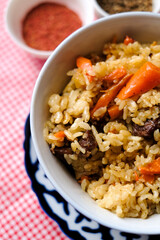 Bowl of asian food pilaf with rise, carrot and spices at table  background