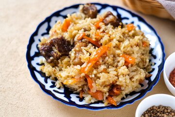 Bowl of asian food pilaf with rise, carrot and spices at table  background