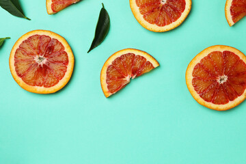 Red orange slices and leaves on mint background