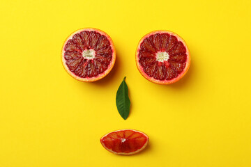 Face made of red oranges on yellow background