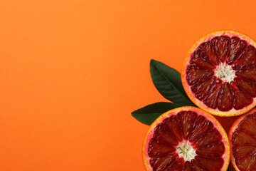Red orange halves and leaves on orange background
