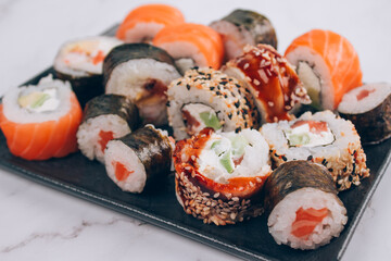 Sushi bar lunch menu - set of sushi rolls with salmon, avocado and smocked eel on white marble table background - futomaki. uramaki, maki and hosomaki. Order food online and home delivery food concept