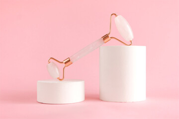 Rose quartz roller for facial massage on a concrete podium. Beauty and home skin care concept. Anti-aging therapy and lifting.