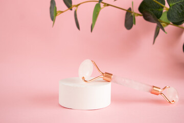 Rose quartz roller for facial massage on a concrete podium. Beauty and home skin care concept. Anti-aging therapy and lifting.