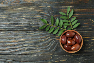 Bowl of red olives, and twigs on wooden background