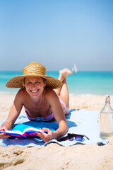 Mid aged woman with short hair relaxing at the beach reading a book
