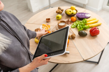 Young beautiful woman using a tablet computer to cook in her kitchen, healthy food.