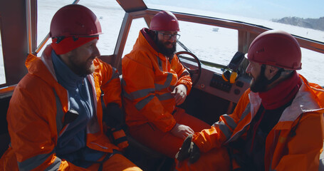Professional rescuers in orange uniform sitting in boat and talking