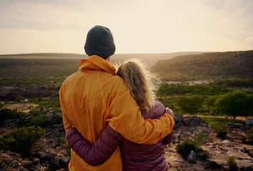 Rear view of young man and woman hugging while looking at beautiful sunrise