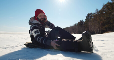 Mam with injured leg sitting on snow outdoors calling 911