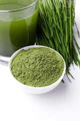 Green Barley Sprout grass and bowl of green detox powder isolated on white. Copyspace.