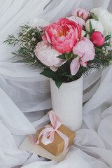 Stylish peonies bouquet, gift, greeting card on background of soft white fabric. Happy Mothers day