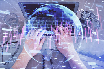 Multi exposure of man's hands typing over computer keyboard and forex graph hologram drawing. Top view. Financial markets concept.