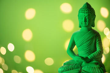 green illuminated stone Buddha statue in front of a green background