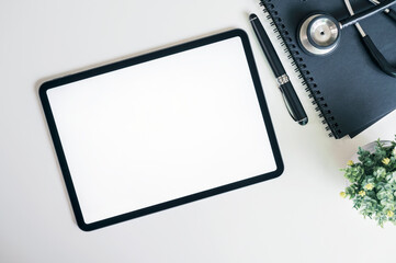 Fototapeta na wymiar Mockup blank screen tablet and stethoscope on white top table, top view.