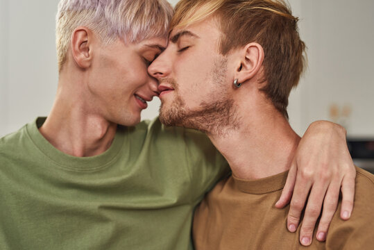 Portrait of tender gay male couple hugging on kitchen
