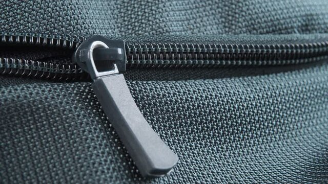 Hand closes the zipper lock of a green textile bag close-up. Macro shot. Travel preparation concept