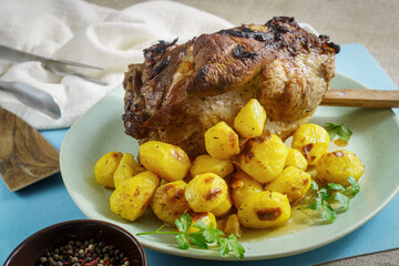 Whole baked pork shoulder with roasted baby potatoes and spices on plate