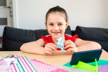 A preschool girl makes an origami frog and a boat from paper, creativity for children, activities...