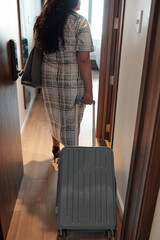 Fototapeta premium Young businesswoman in long dress entering hotel room she came on business trip