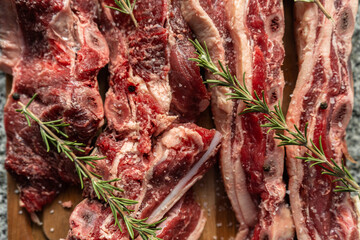 Close-up of raw beef seasoned with rosemary. Short ribs ready to cook.