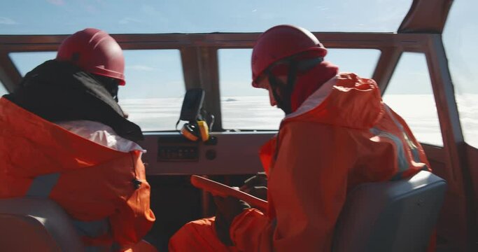 Lifeguards in hovercraft talking on walkie-talkie and using digital tablet navigating in arctic