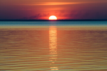 Bright beautiful sunset at the calm sea. Solar disk over water.