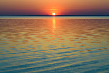 Bright beautiful sunset at the calm sea. Solar disk over water.
