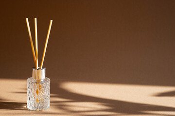 Aromatic reed air freshener on brown background hard shadow. Aromatherapy sticks. Air refresher...