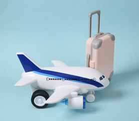 Travel concept. Toy passenger plane and luggage on a blue pastel background.