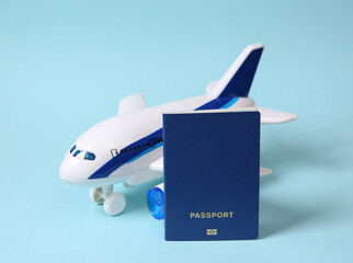 Travel concept. Toy passenger plane and paqssport on a blue pastel background.