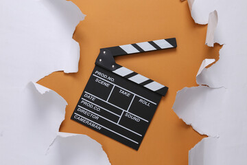 Movie clapboard and torn paper sheets on beige background. Top view