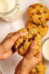 mano partiendo a la mitad una galleta con chispas de chocolate y rellena de chocolate