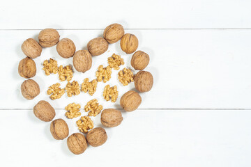 heart made of whole walnuts and kernels on a light wooden background, copy space, space for text