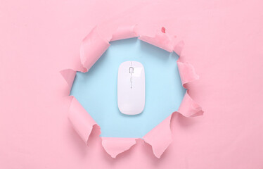 Pc mouse through torn hole on blue-pink pastel background. Business concept. Pastel color trend....