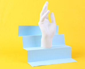 Stand hand on stairs, yellow background. Concept art, minimalism