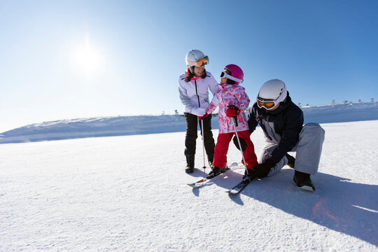 Young parents teaching daughter to ski