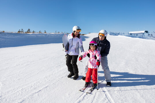 Young parents teaching daughter to ski