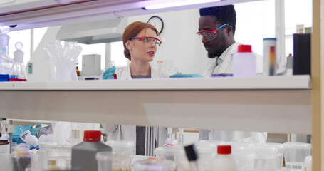 Diverse young scientists holding test tubes with sample developing vaccine in laboratory