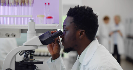 African-american man making medical research using microscope working in lab