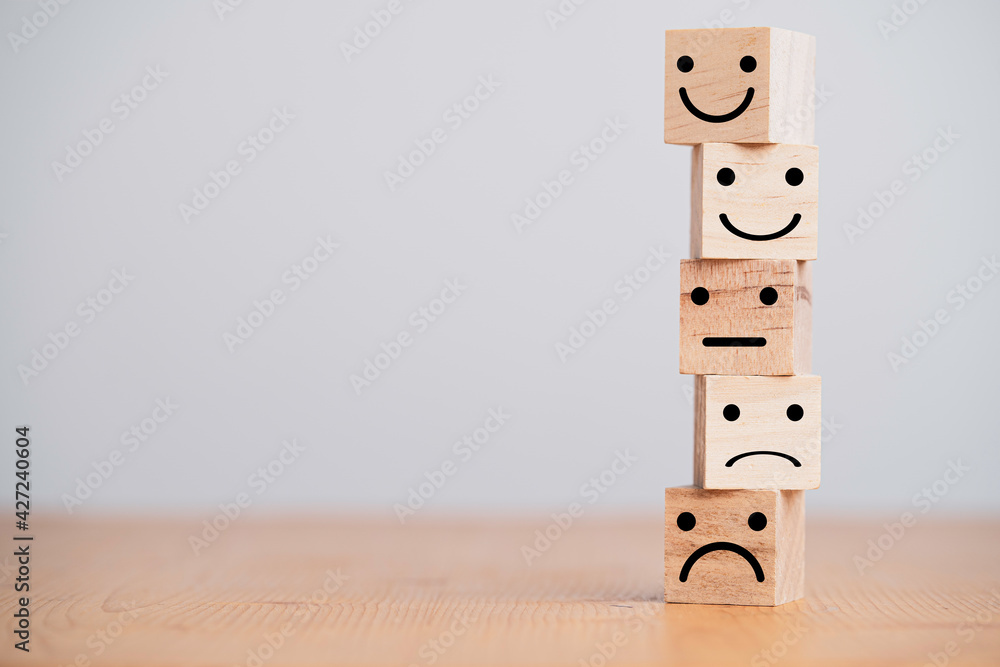 Poster Customer satisfaction survey concept, human face icons print screen on wooden cube block on table for evaluate product and service.