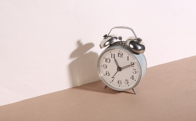 Creative still life. Retro alarm clock on beige brown background. Minimalism. Trendy shadow.