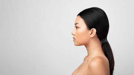 Asian Woman Looking Aside Posing Shirtless, Gray Background, Side-View Portrait
