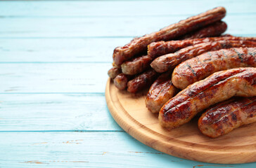 Grilled sausages on wooden board on blue background with copy space