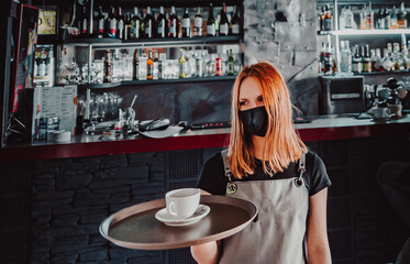 Portrait young waitress standing in cafe. girl the waiter holds in bunches a tray with utensils. Restaurant service