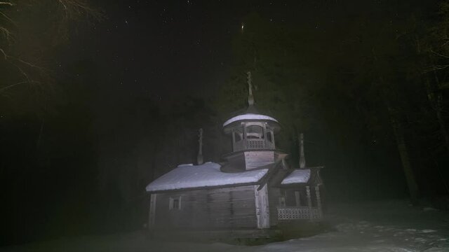 Old abandoned wooden church in the forest under the stars