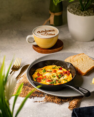 huevos mediterraneos en sarten sobre bandeja acompañados de rodajas de pan