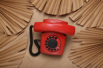 Creative layout. Retro rotary phone and palm leaves on beige background. Flat lay