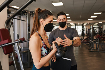 Personal trainer and fit woman training wearing face masks during pandemic